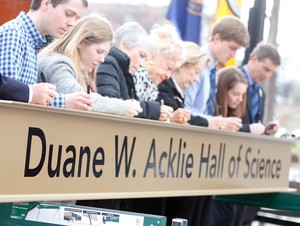 Members of the Acklie family are the first to sign a beam