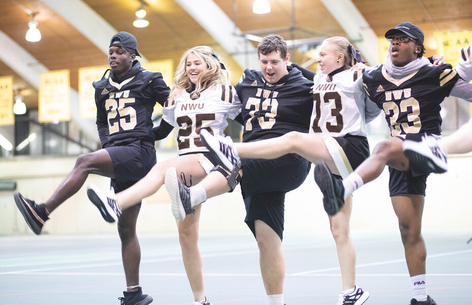 Students wearing NWU jerseys form a kick line in the Field House.