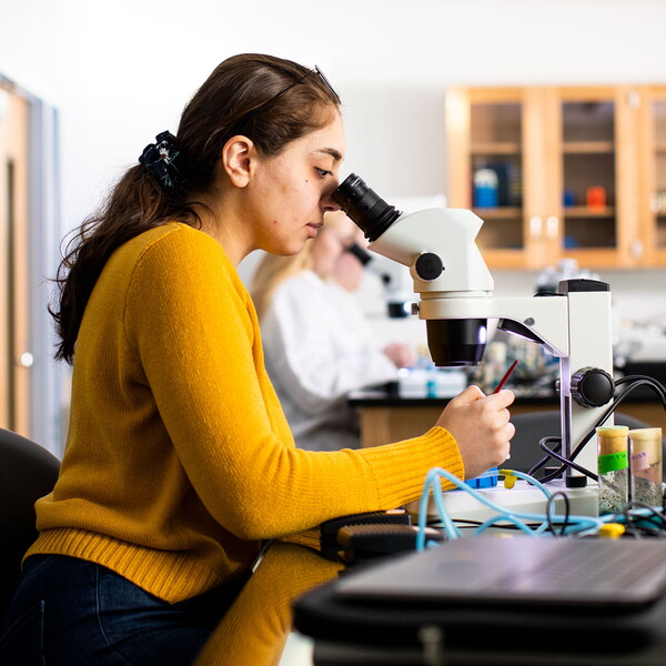 Female student looking through microscope.