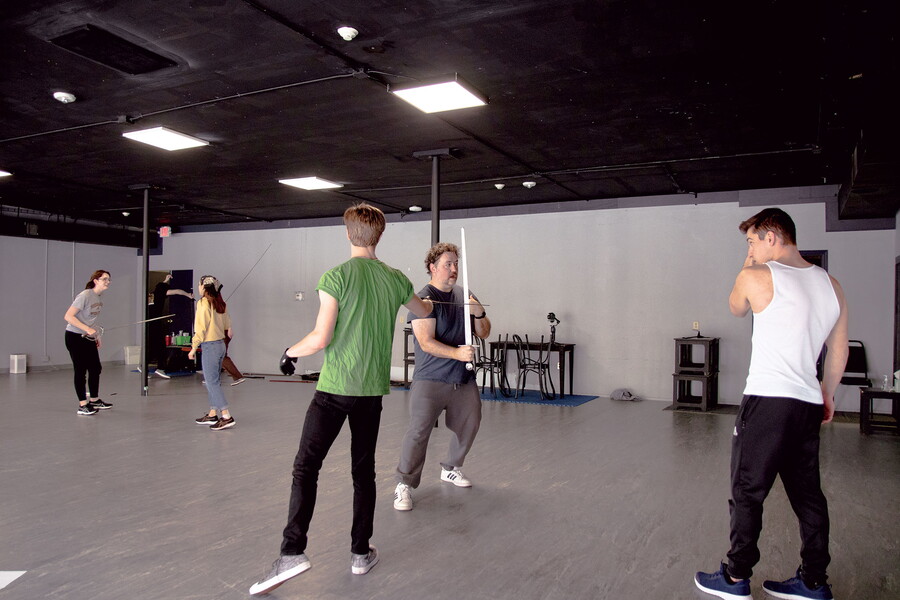 Theatre professor instructs acting students in sword combat.