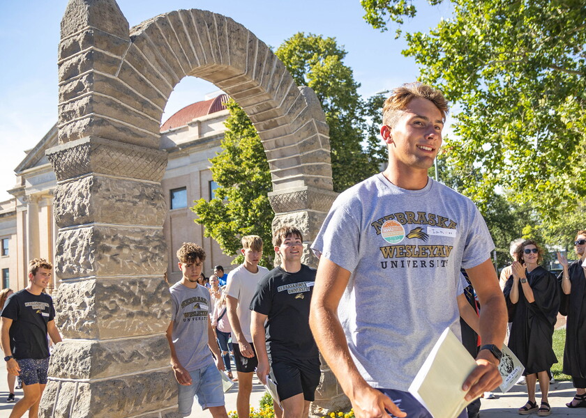 Students walk thru the stone arch with faculty, staff and parents cheering.