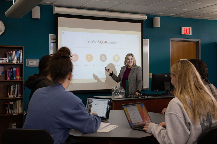 Cooper Center for Academic Excellence director points to a slide projected on a screen in front of students.