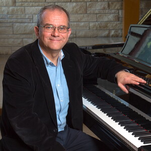 Dr. Slawomir Dobrzanski sitting at a grand piano.