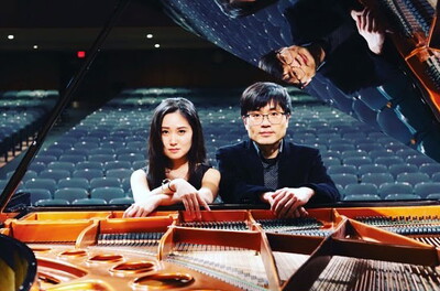 Feifei Jiang and Peter Jiang sitting at a grand piano.