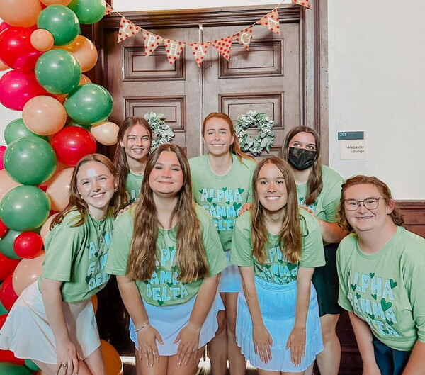 Seven Alpha Gamma Delta women in front of the Alabaster Lounge smiling.