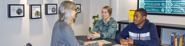 Janelle Andrineini sits across from a female and male student in the Career Center.