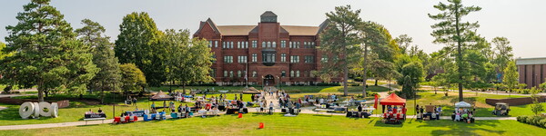 Tables set up in front of Old Main with people scatter throughout the lawn.